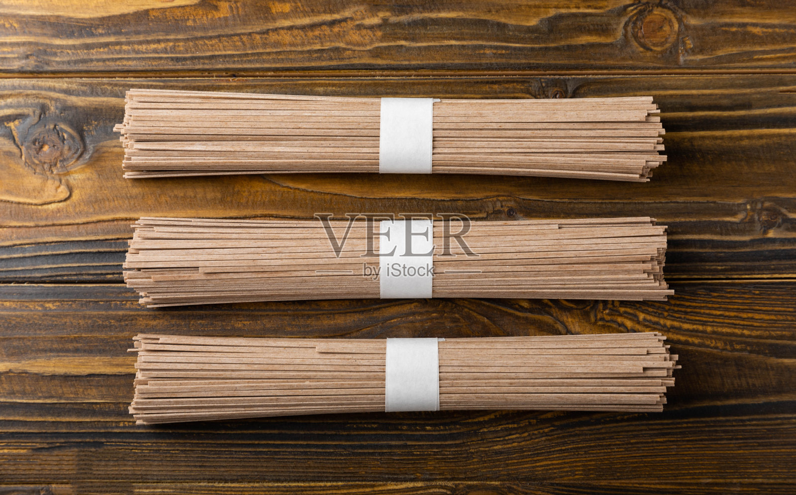 荞麦面，棕色纹理，木质背景。生面条。无麸质菜肴的配料。干荞麦荞麦面。日本传统食物。健康食品。复制的地方。照片摄影图片