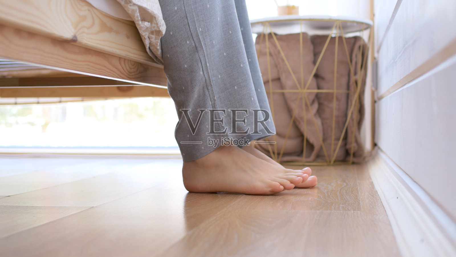 女人光脚特写，一个女人下了床，光着脚站在地板上。早上在卧室里，看到一个女孩的腿谁醒来和下床。照片摄影图片