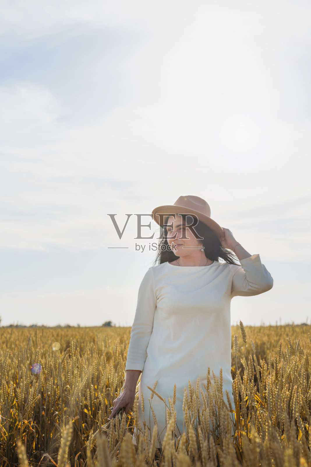 中年妇女在白色连衣裙站在麦田与日出的背景，背影照片摄影图片