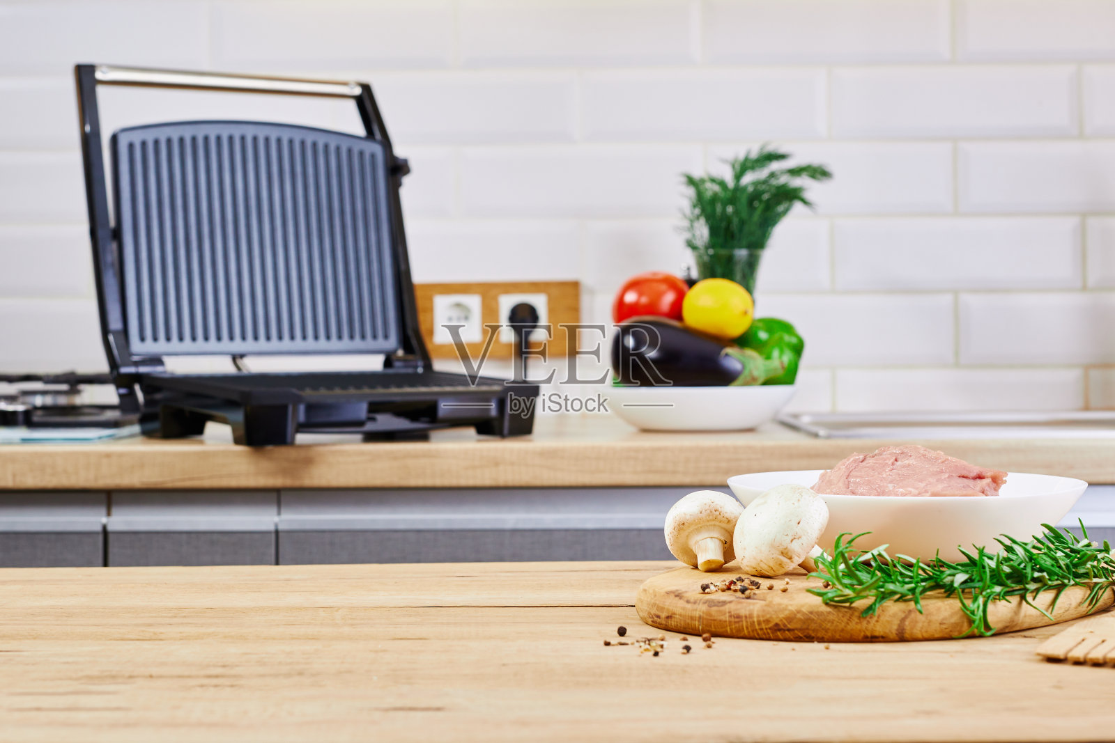 在厨房内部准备烧烤。电烤架烧烤和肉类在厨房的桌子上。照片摄影图片