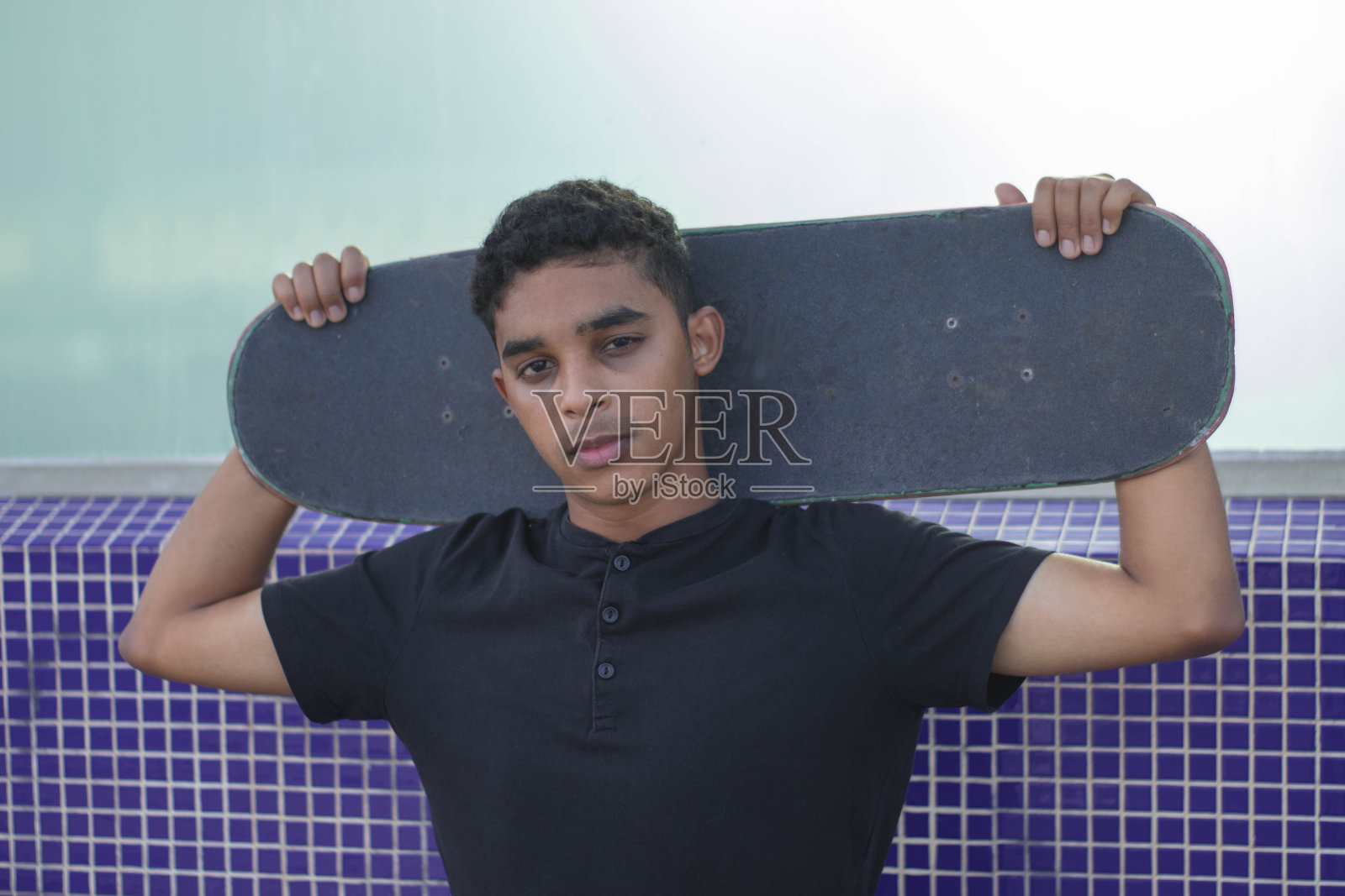 年轻的拉丁男子与滑板的近距离照片。看镜头。照片摄影图片