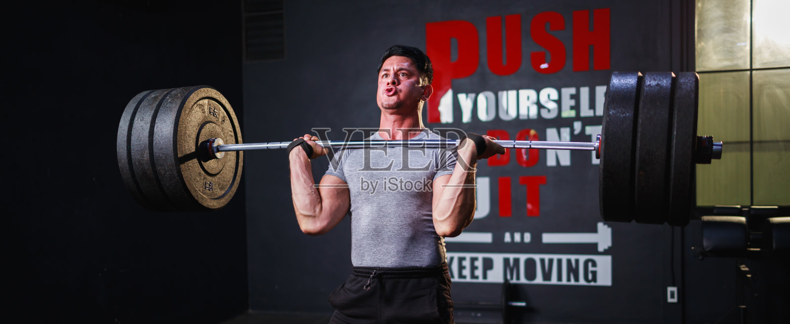 横幅大小的年轻健美运动员在健身房做肩部杠铃运动照片摄影图片