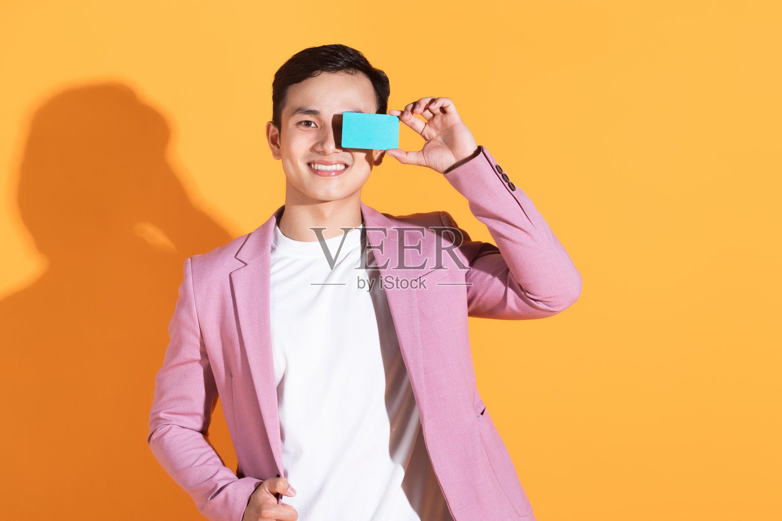 图片上的年轻亚洲男子手持银行卡，背景是atm卡照片摄影图片