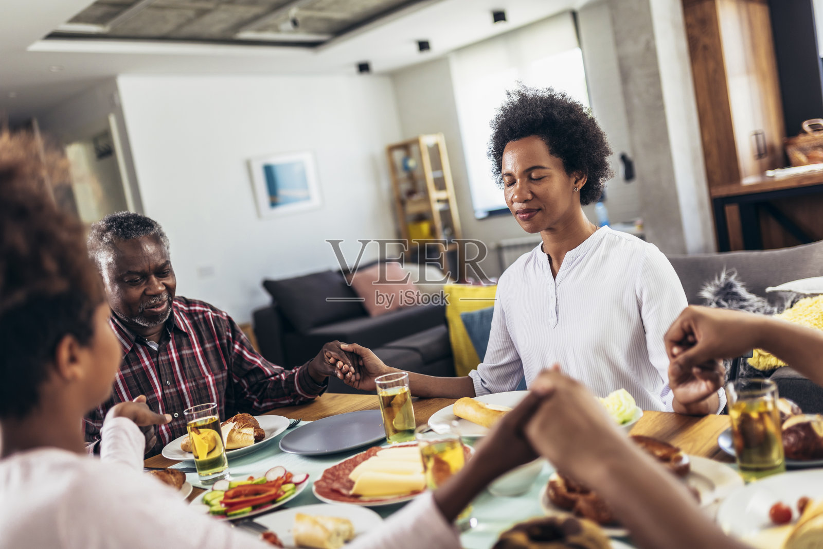 一个多代美国黑人家庭在餐桌上手牵着手祈祷照片摄影图片