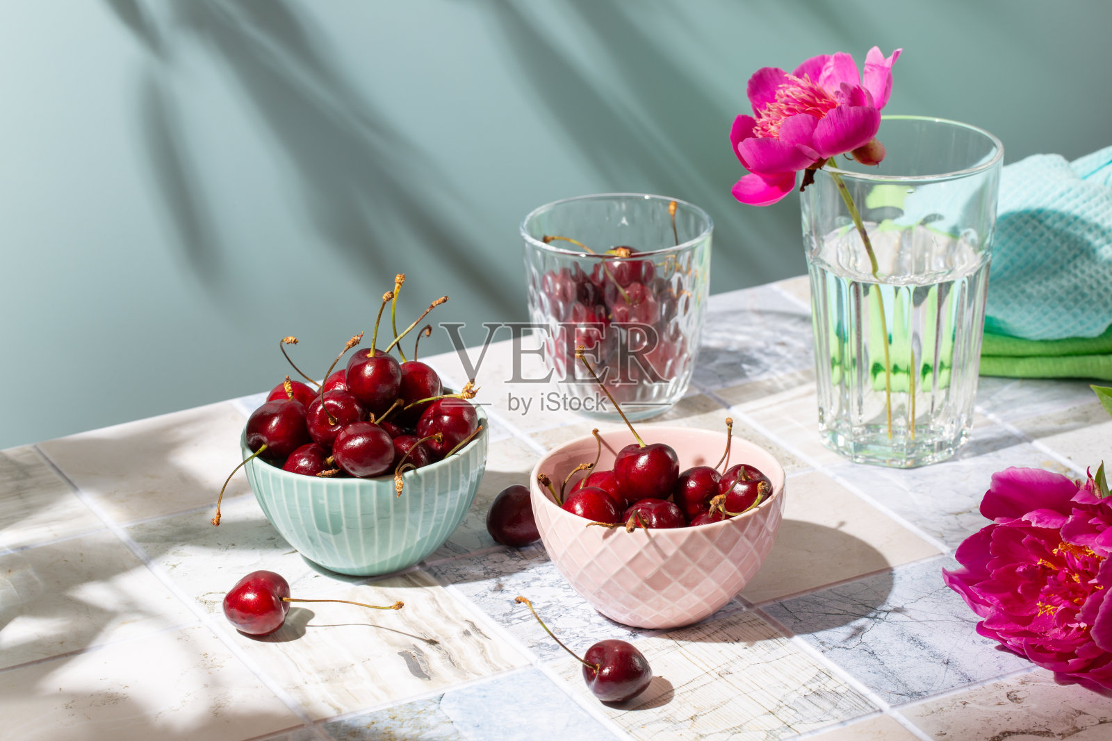 红色甜樱桃浆果放在瓷砖桌子上，对着蓝色的墙。夏天的概念。照片摄影图片