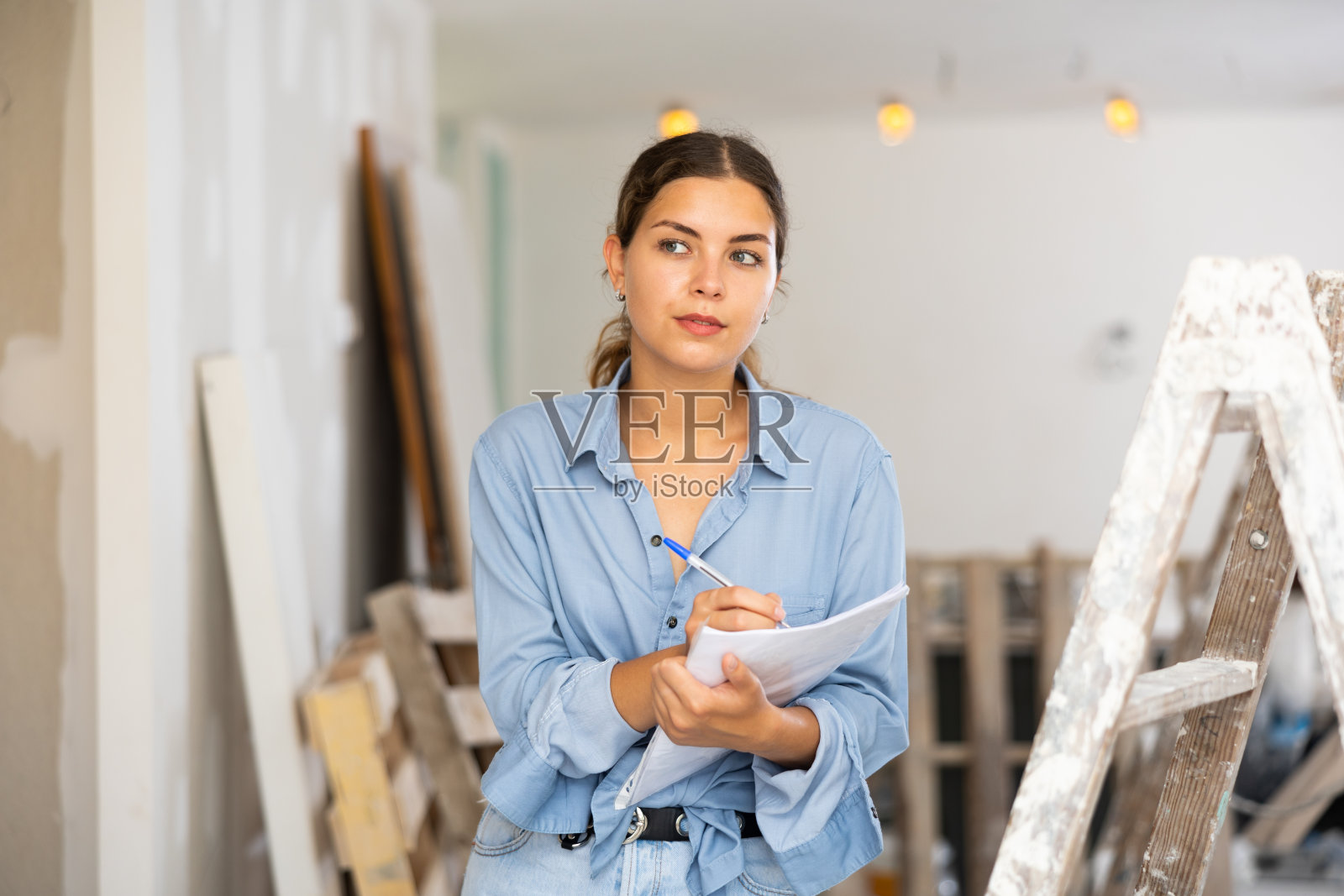 一名妇女手里拿着文件，检查小屋内已完成维修的质量照片摄影图片