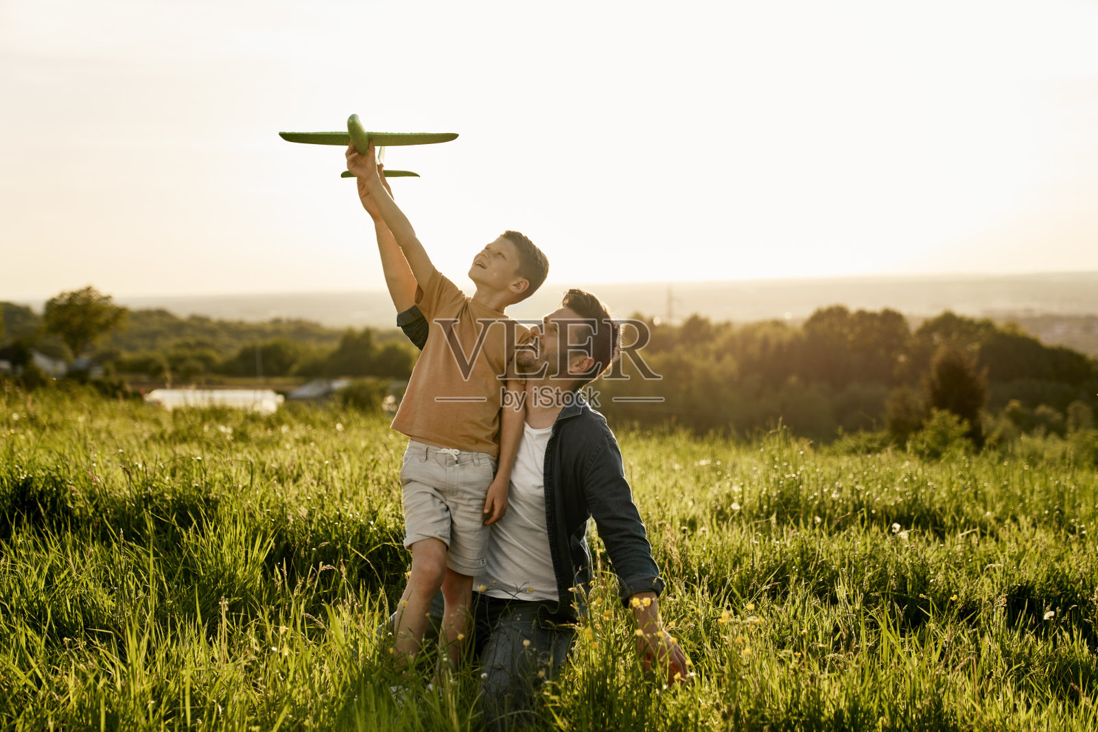 小男孩和爸爸在草地上玩玩具飞机照片摄影图片
