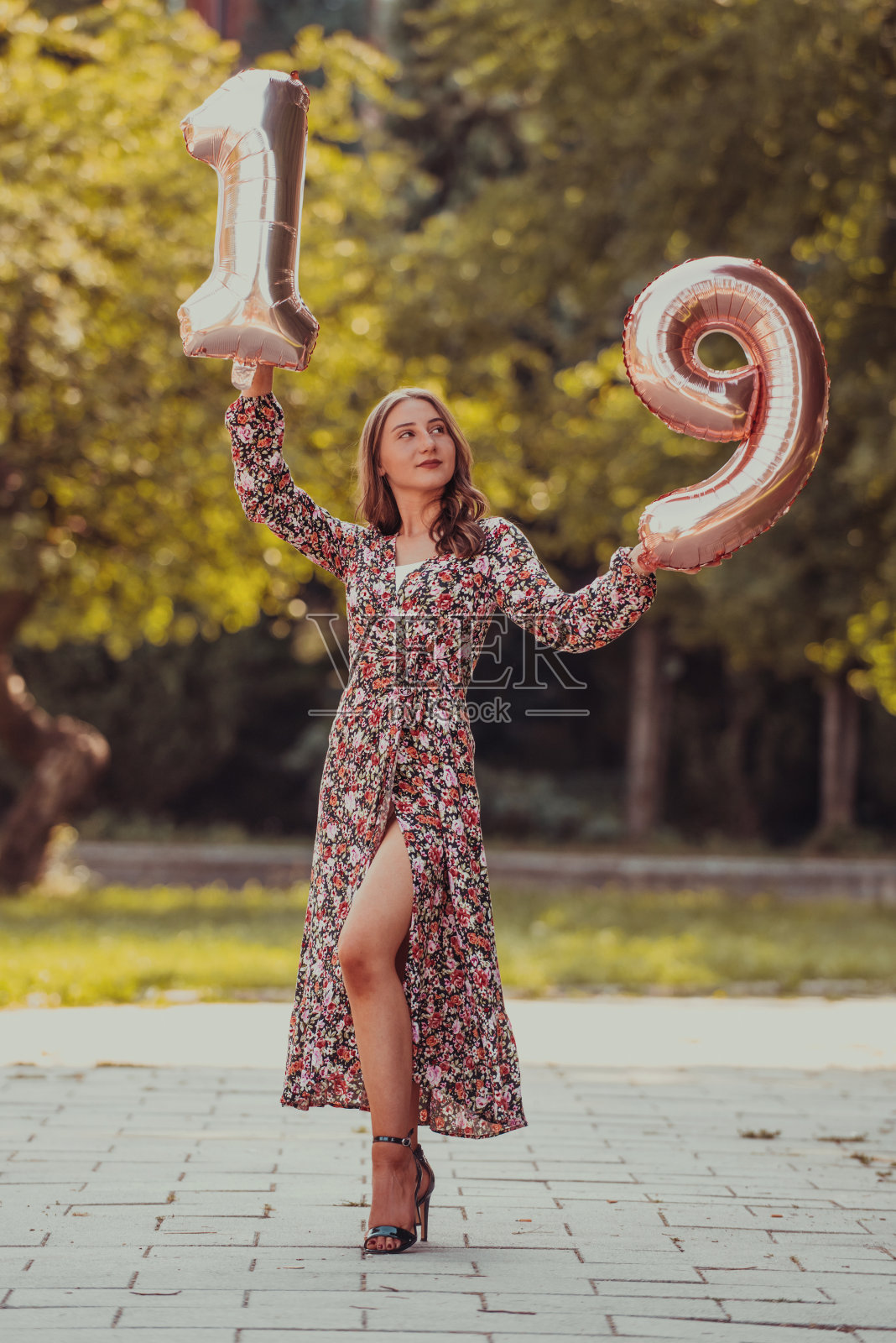 一个十几岁的女孩被拍到在公园里的生日号码旁边照片摄影图片