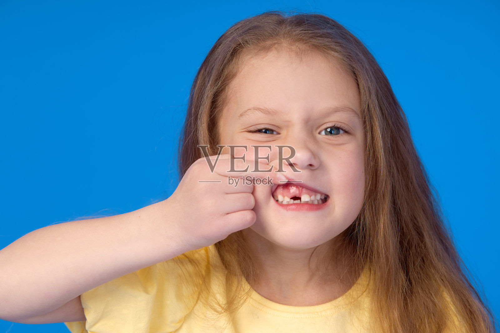 无孩子。可爱的小女孩在蓝色的背景上笑得很开心。第一颗乳牙掉了。儿科牙科与口腔卫生的概念照片摄影图片