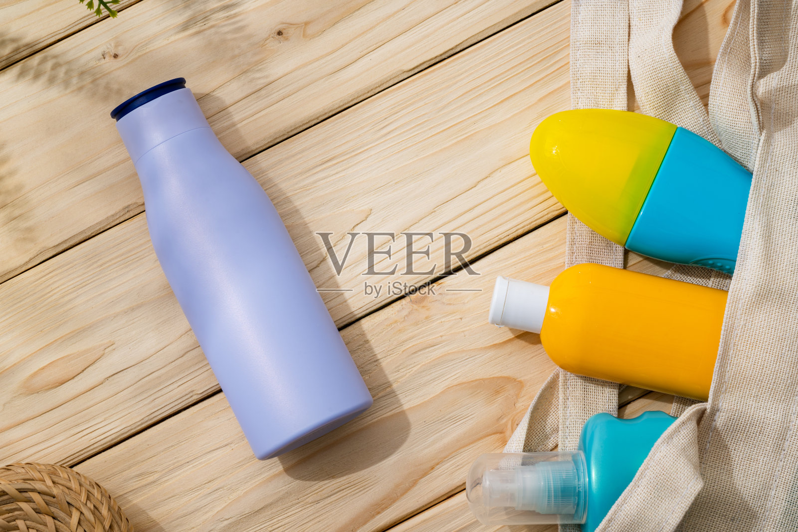 在木制背景的沙滩袋里的防晒霜瓶子照片摄影图片