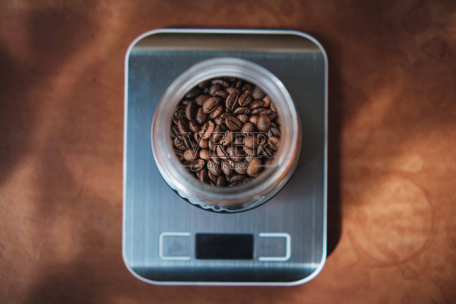 电子秤上的玻璃罐里的咖啡豆，旁边有一个手动咖啡研磨机。照片摄影图片