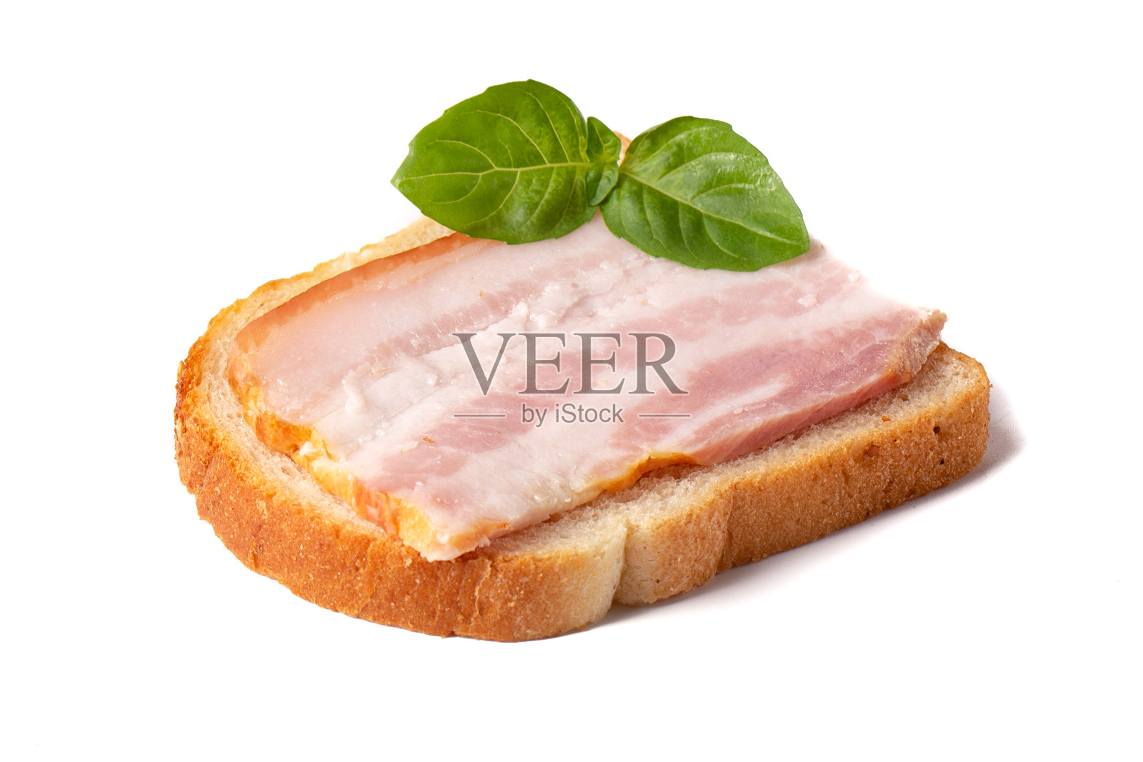 一片新鲜的培根，上面有一片绿色的罗勒叶，上面是一片白色的小麦面包，背景是白色的。照片摄影图片