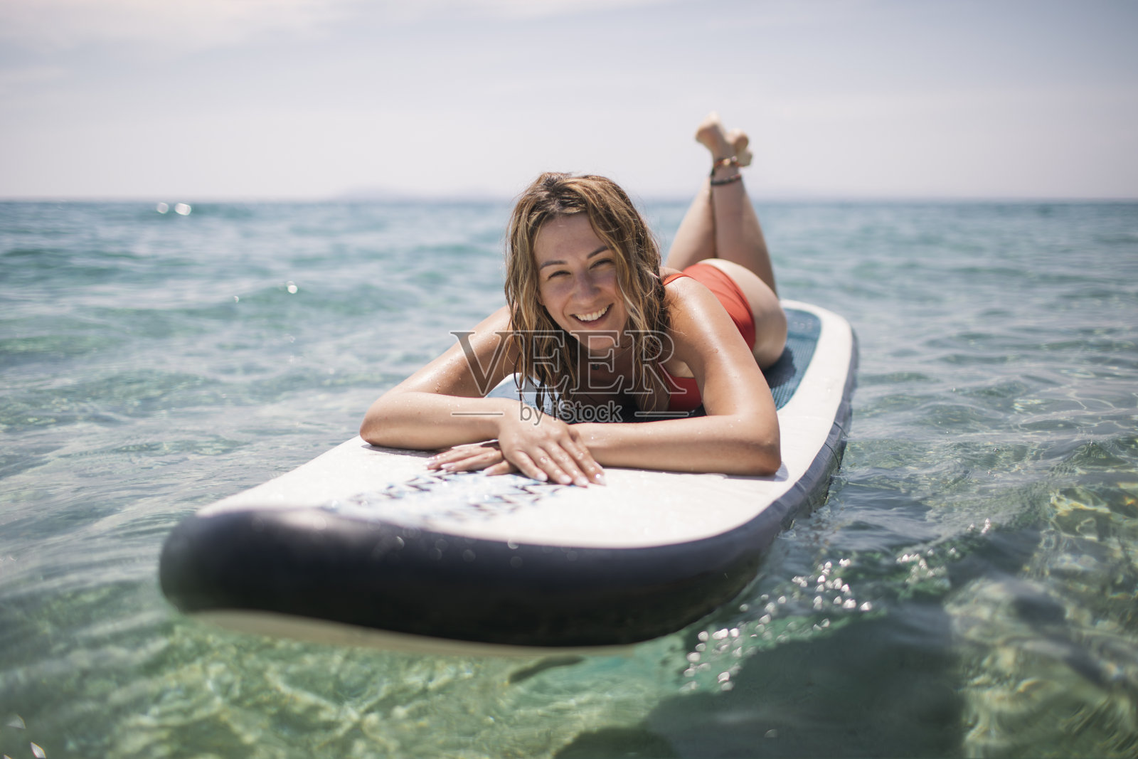 微笑的女人在桨板上晒太阳照片摄影图片