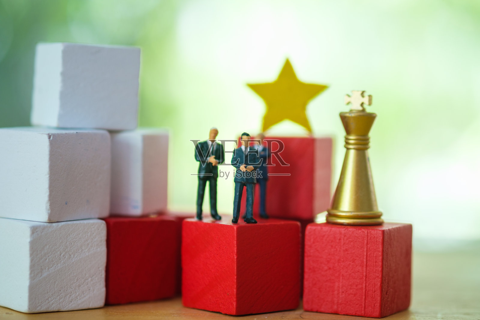 集团商人微型人物站在红木方块与一个黄金骑士棋子和黄色的星。商业中的奖励概念照片摄影图片