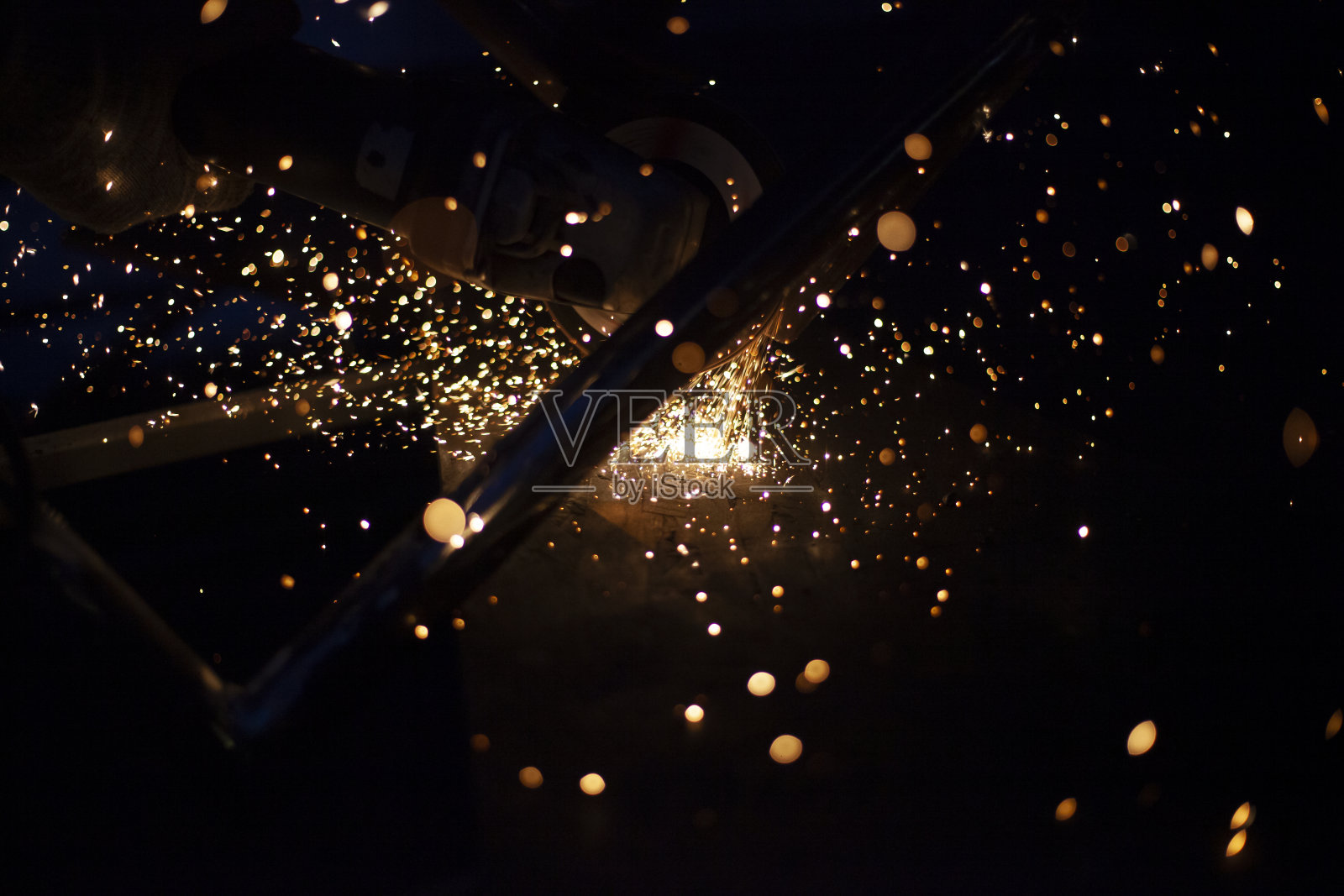 磨金属产生的火花。车间钢材加工。灯光在黑暗。生产的零件。切割成为磨床。照片摄影图片