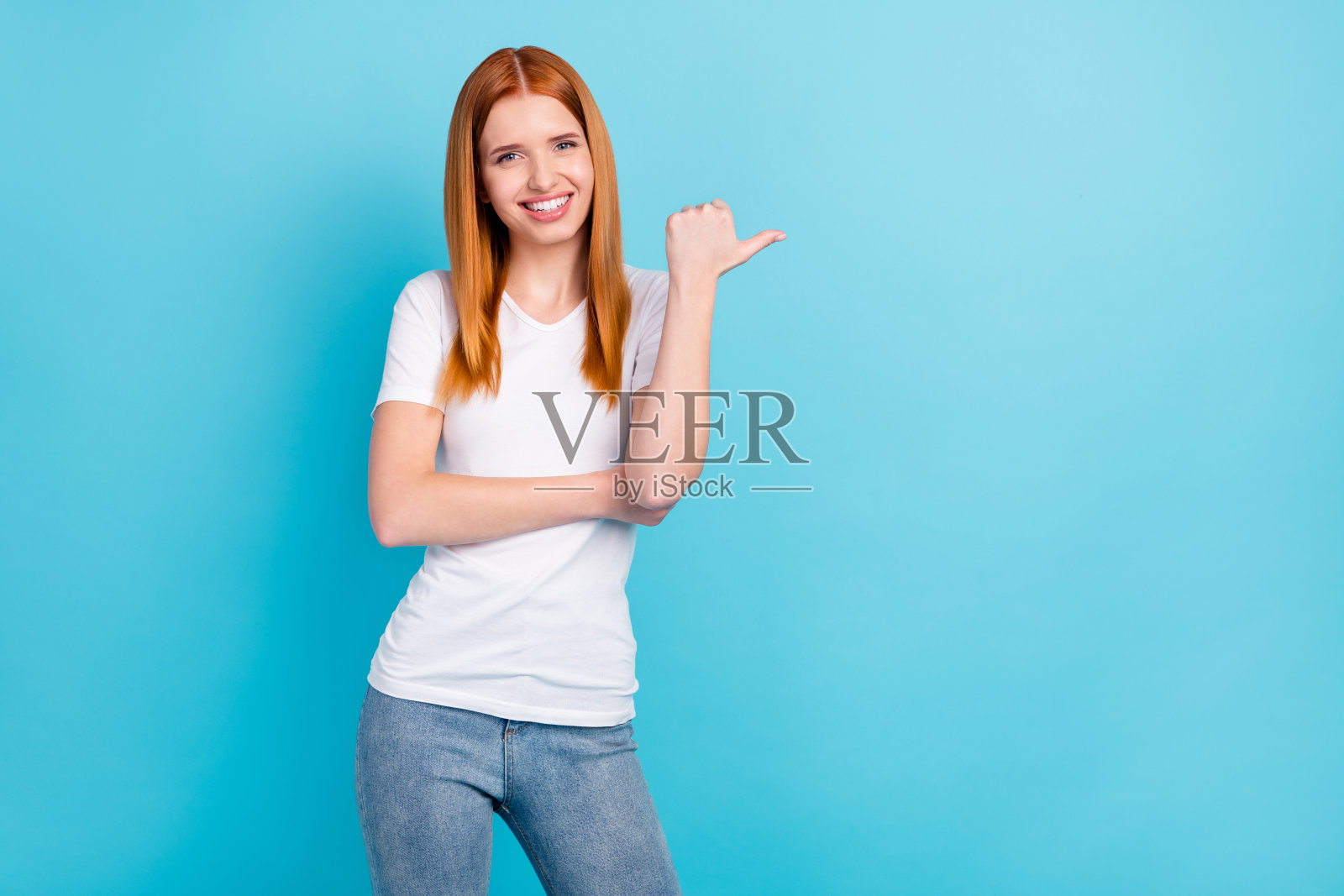 年轻迷人的女孩的照片快乐积极的微笑点拇指空空间广告建议选择孤立的蓝色背景照片摄影图片