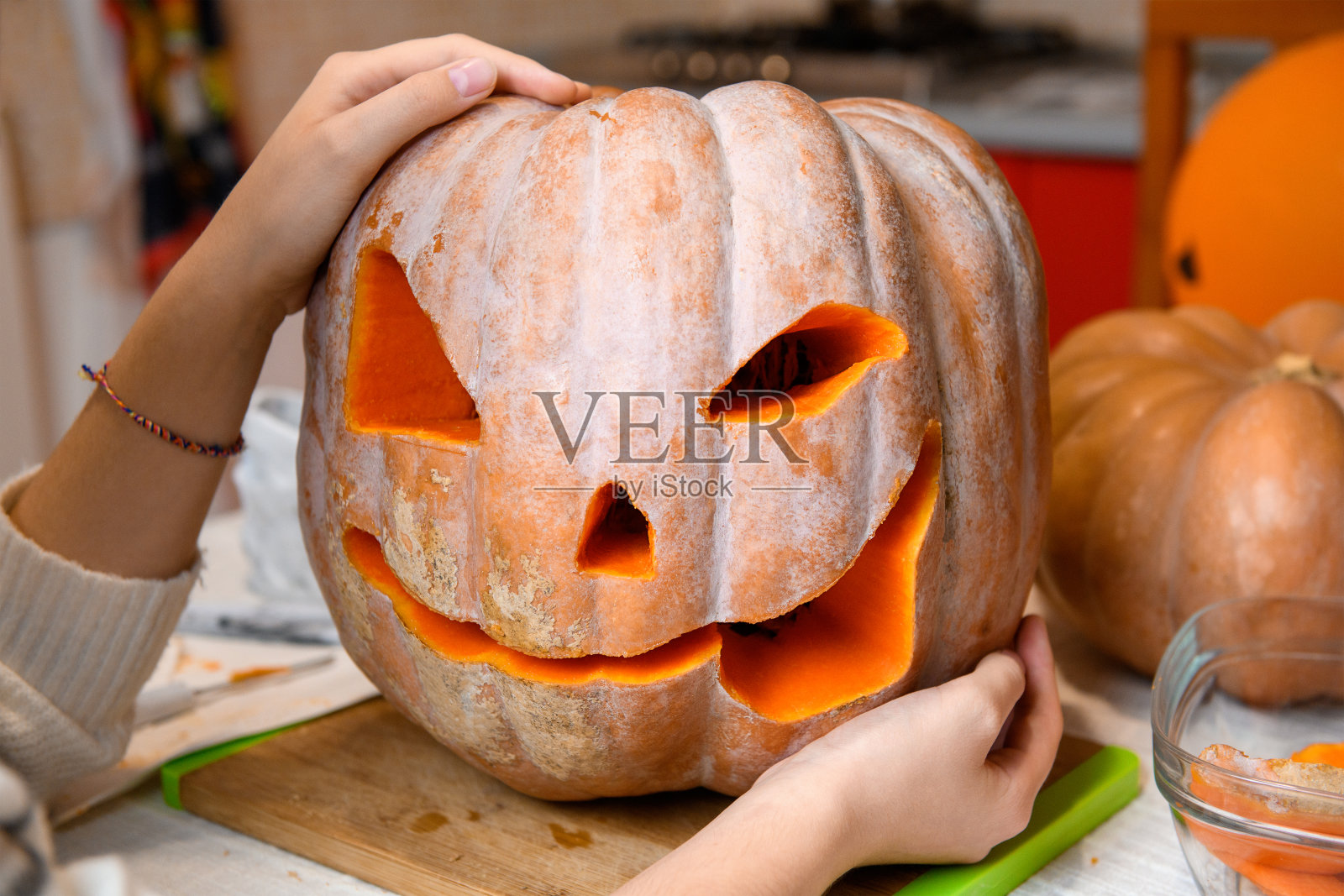 特写女人的手用刀雕刻万圣节派对的大橙色南瓜杰克灯照片摄影图片