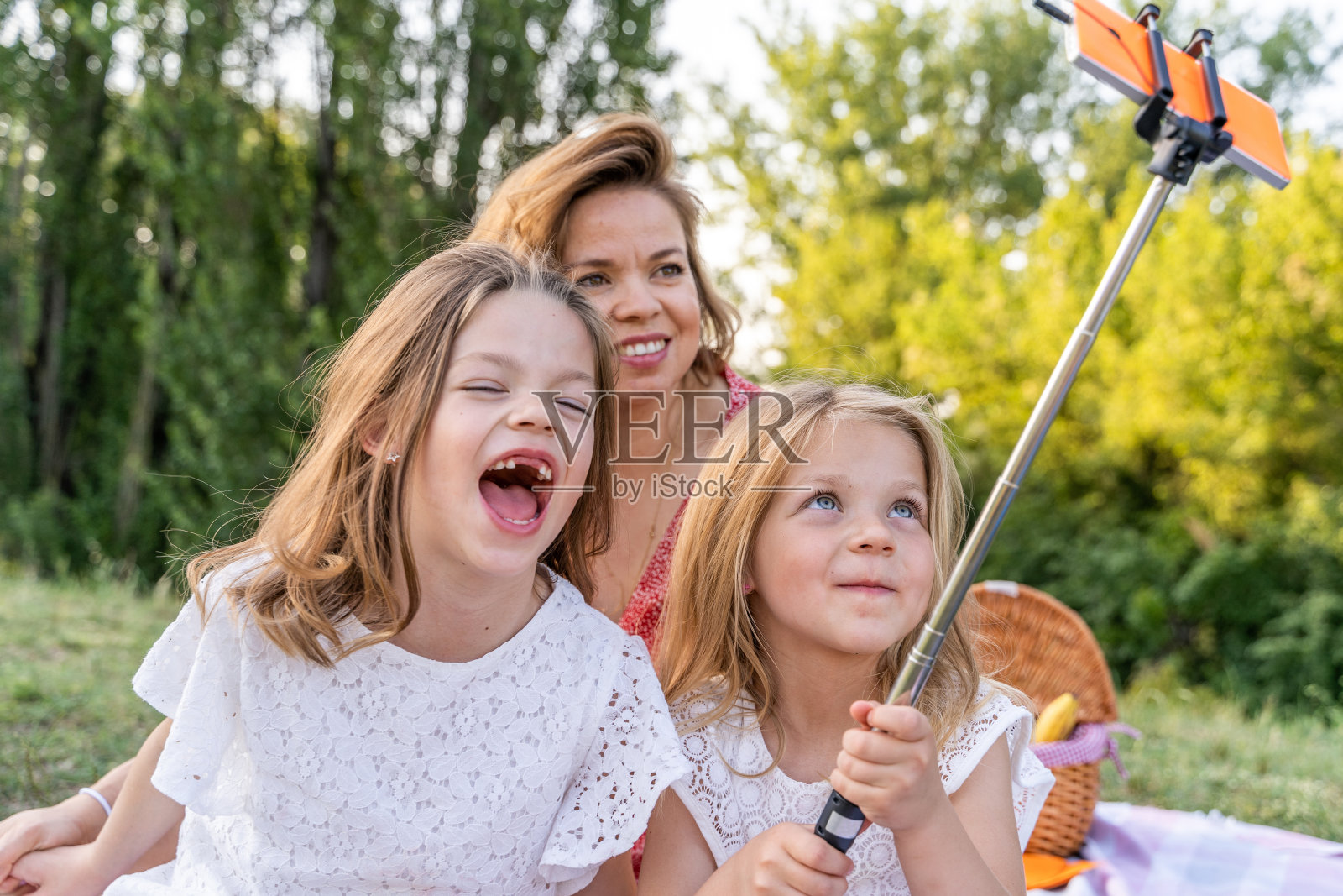 穿着红裙子的年轻妈妈和她的两个女儿在户外自拍照片摄影图片
