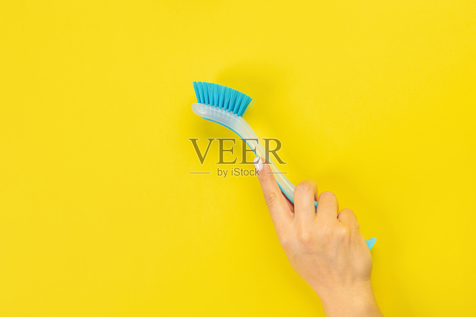 家庭主妇手里拿着一把清洁刷。黄色背景上的空白文本或标志。早春或定期大扫除。清洁和清洗理念。照片摄影图片