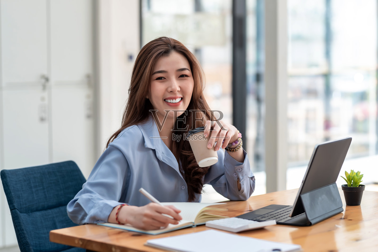 迷人的亚洲女商人喝咖啡准备在办公室工作。看相机。照片摄影图片