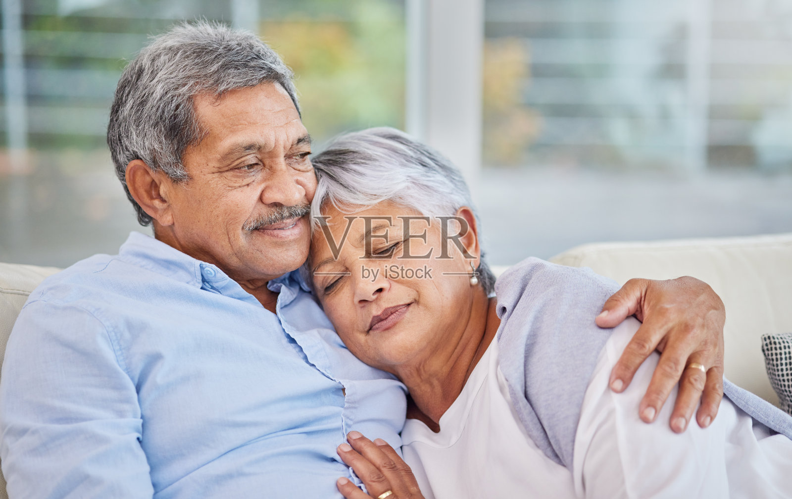 亲密的混合种族年长夫妇放松在他们的客厅在家里的特写。西班牙裔男子和妻子在客厅的沙发上亲密无间照片摄影图片