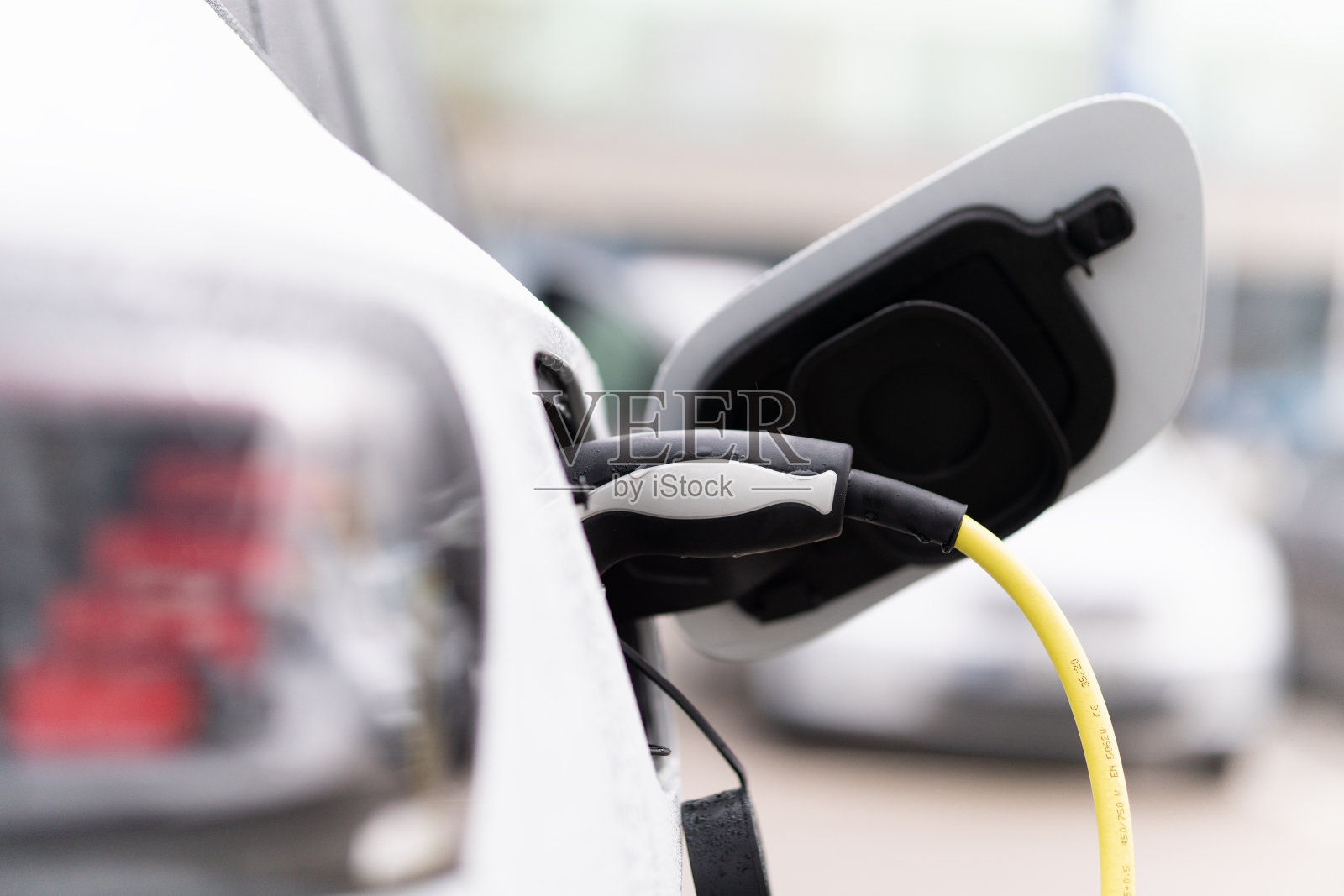 用黄色电缆给家里的电动汽车充电照片摄影图片