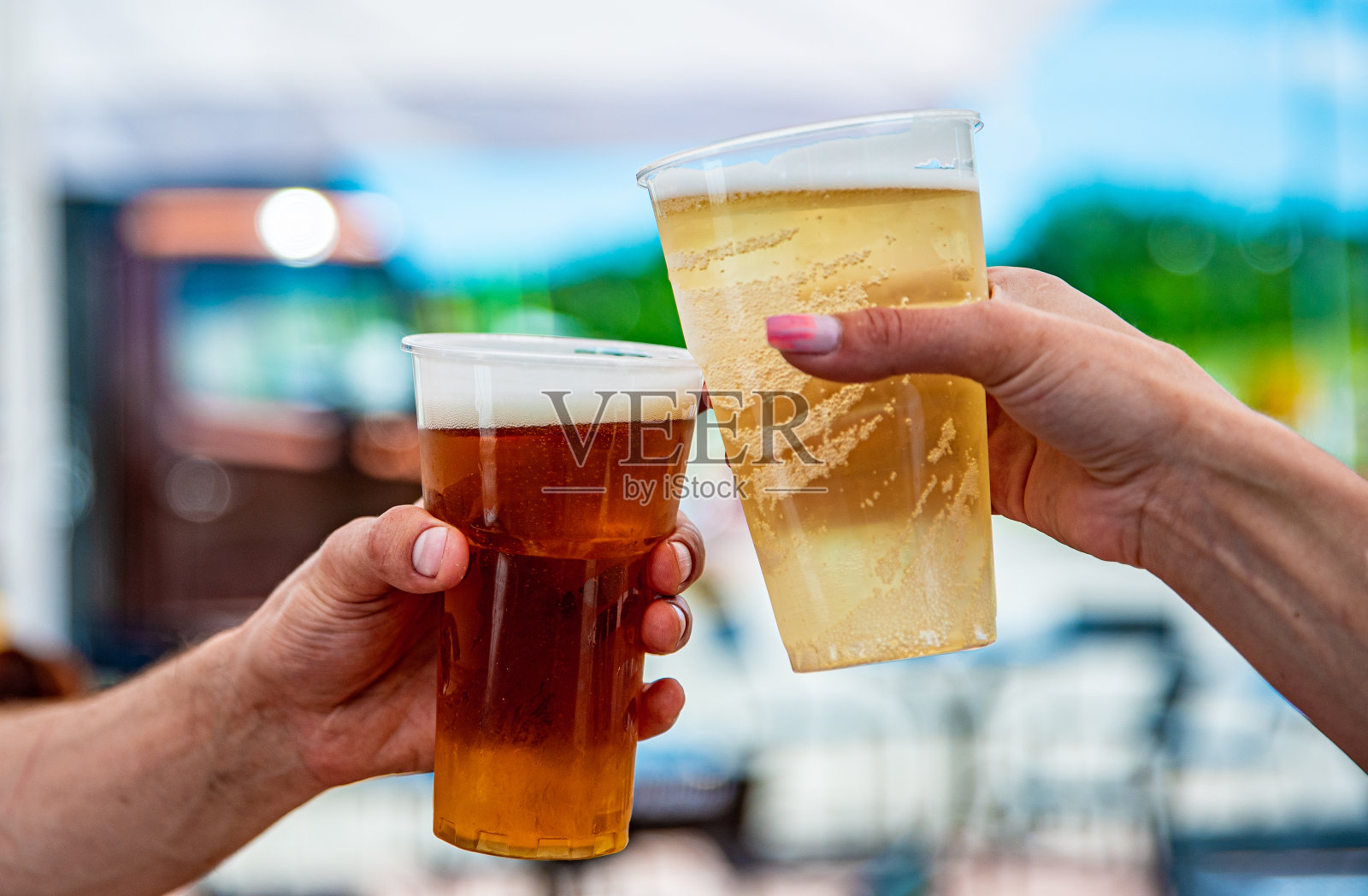 手里拿着两个塑料杯的啤酒。啤酒无比的户外照片摄影图片
