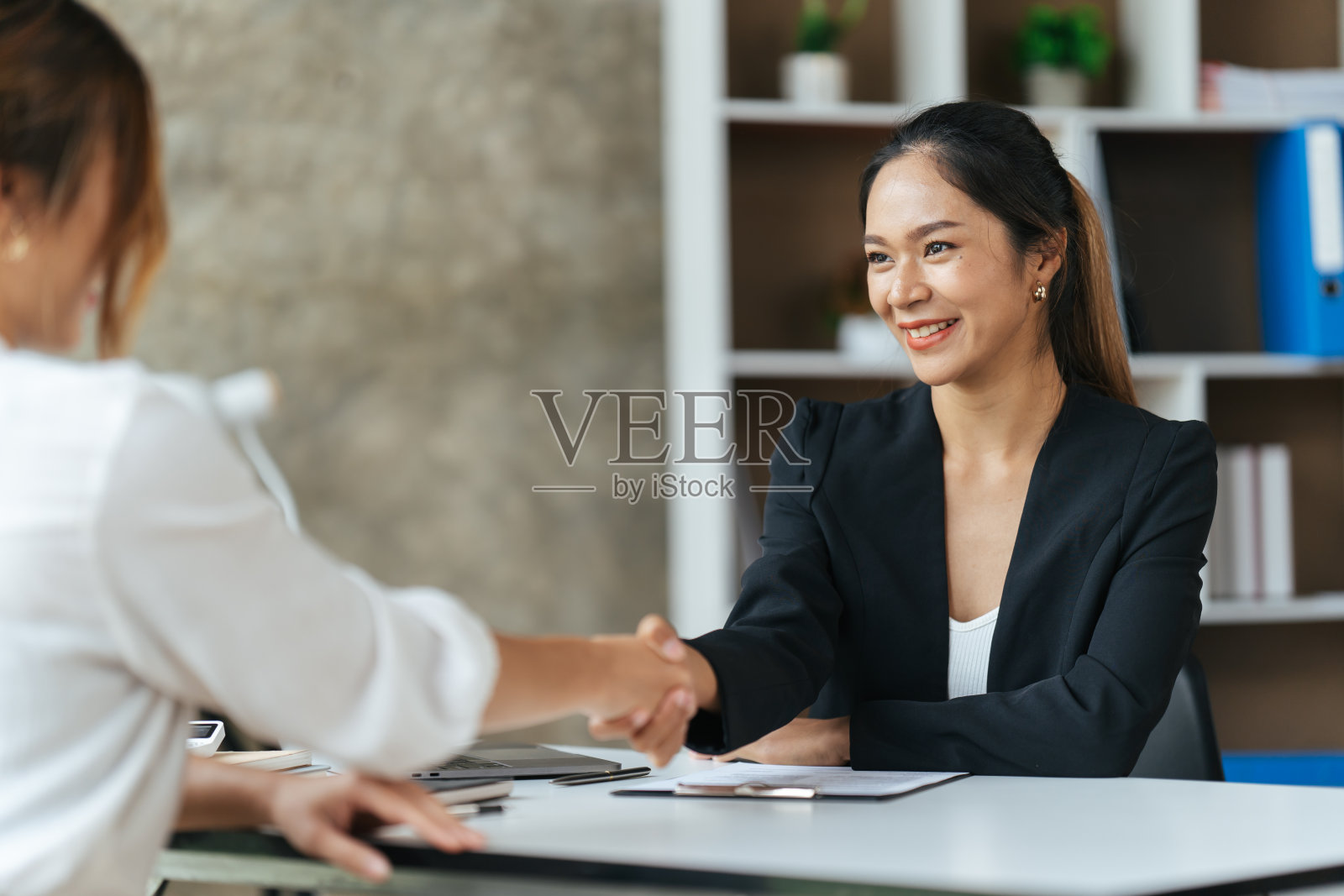 两个女商人握手在现代办公室里，成功的商人握手。照片摄影图片