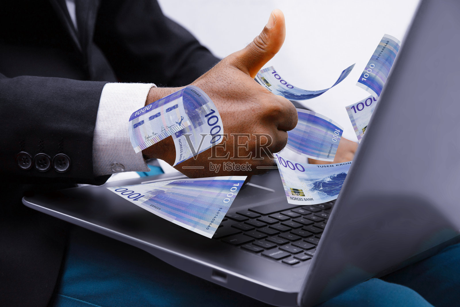 1000挪威克朗纸币从笔记本电脑出来，商人竖起大拇指，金融概念。用笔记本电脑在互联网上赚钱照片摄影图片