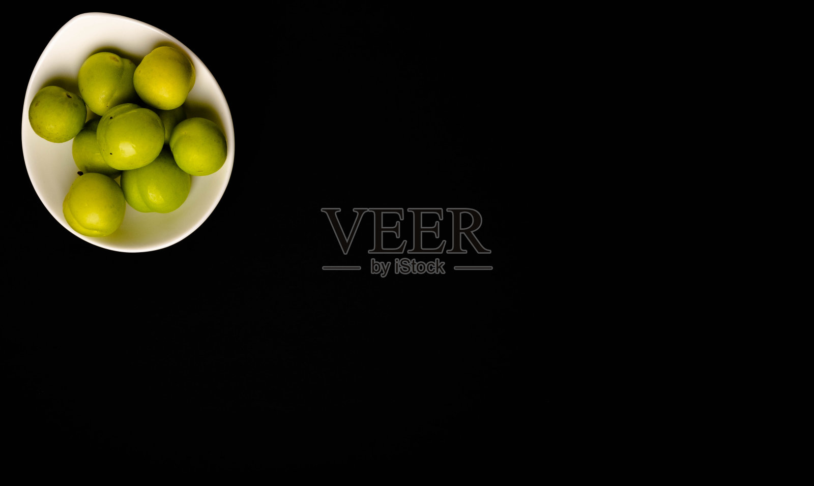 黑色背景上的青青的李子照片摄影图片