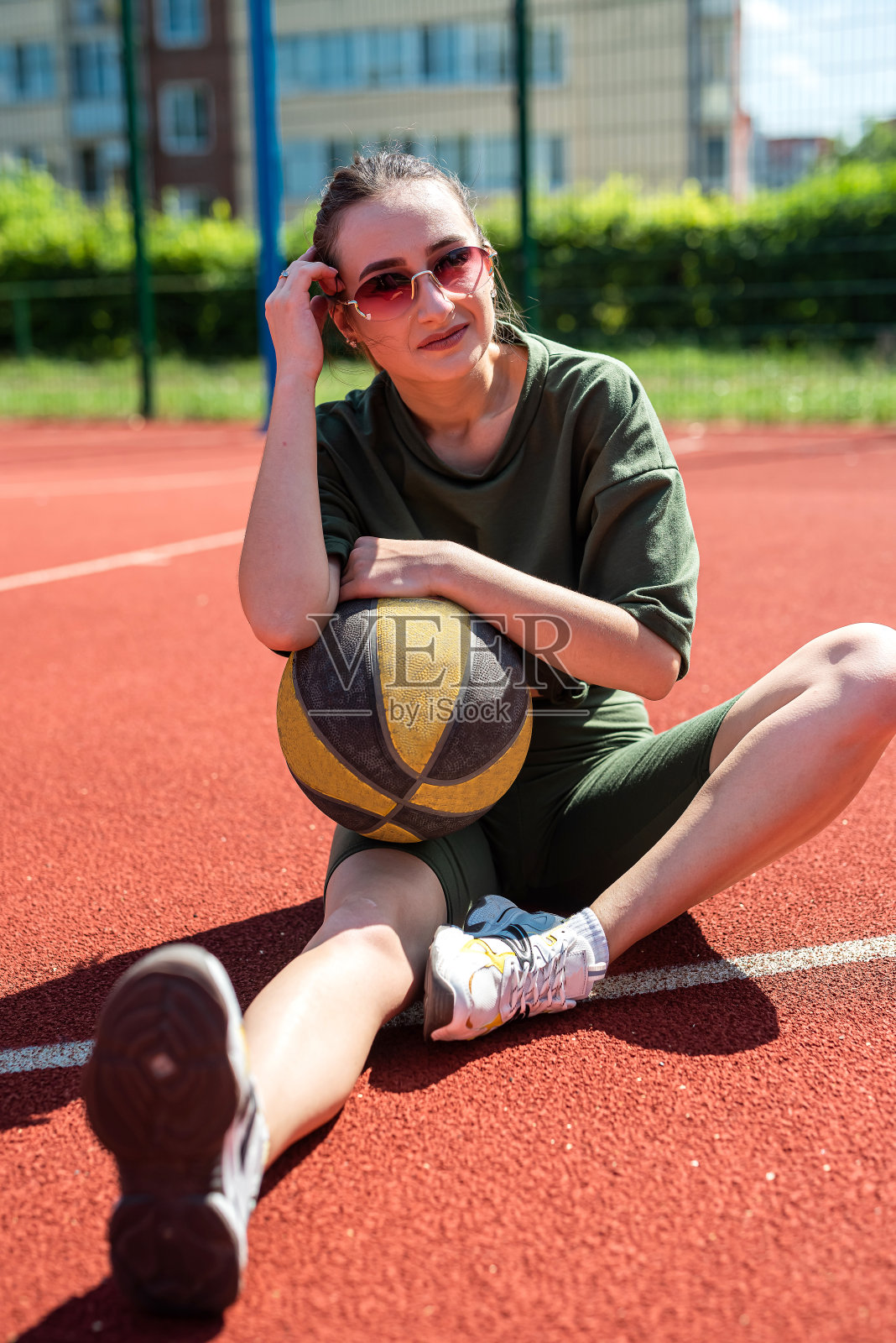 迷人的年轻女子穿着运动服与篮球是休息后的锻炼。照片摄影图片