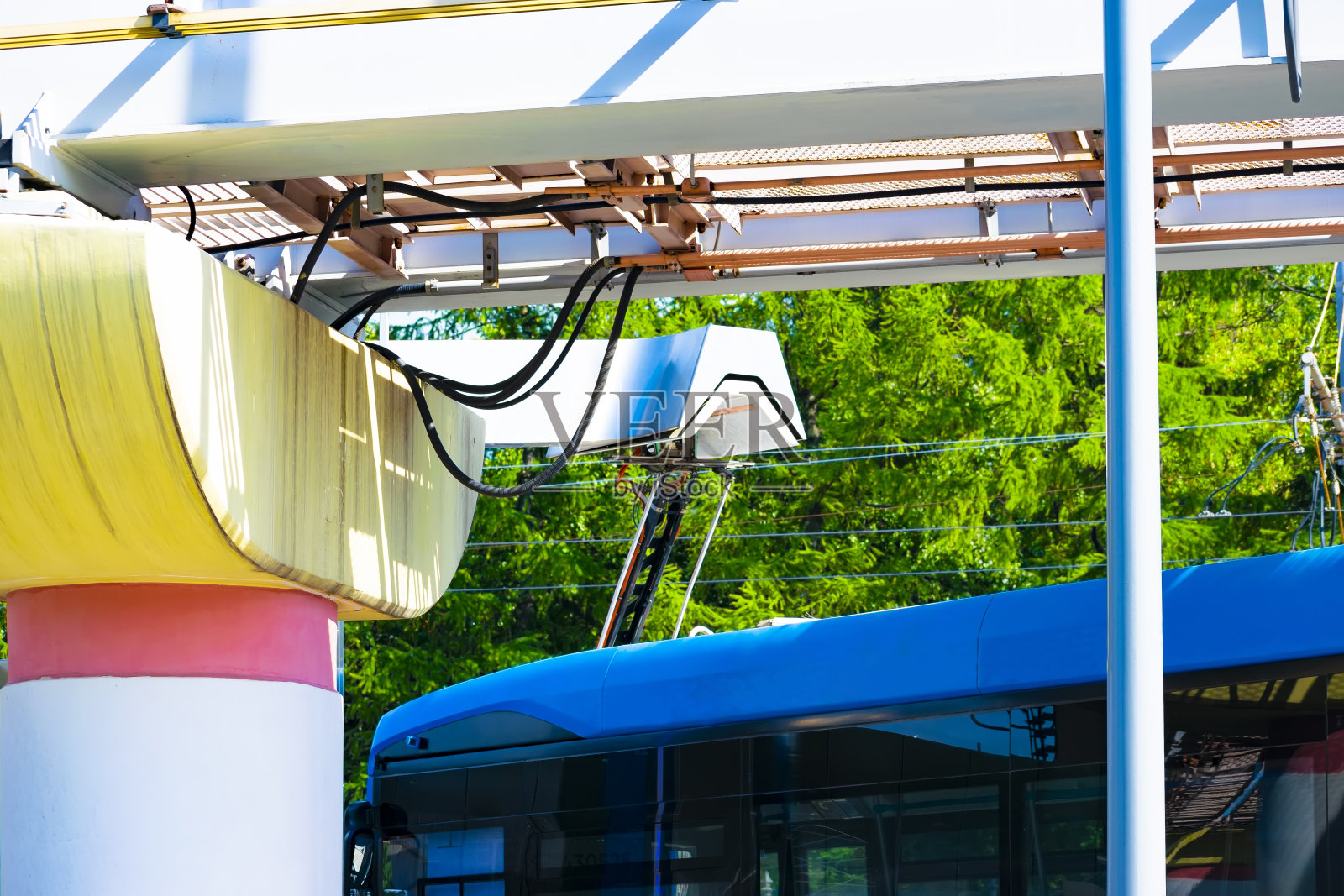 蓝色的电动巴士使用受电弓在充电站为电池充电。环保公共城市交通的概念照片摄影图片