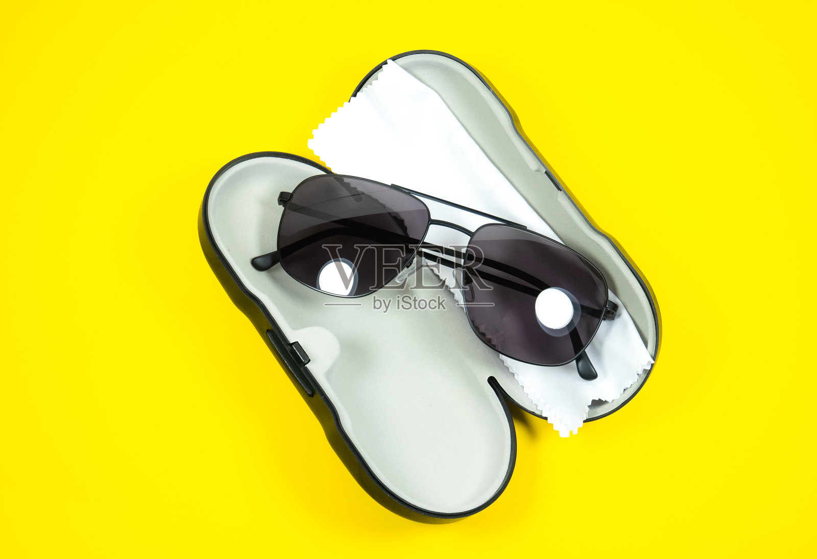 黑色框架的男子太阳镜与眼镜清洁布和案例上的黄色背景。照片摄影图片