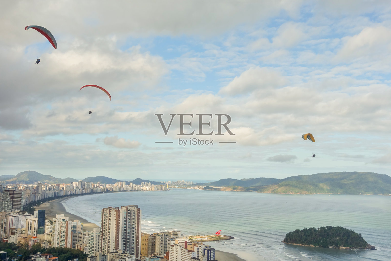 在巴西桑托斯市海滩多云的天空上飞行的滑翔伞照片摄影图片