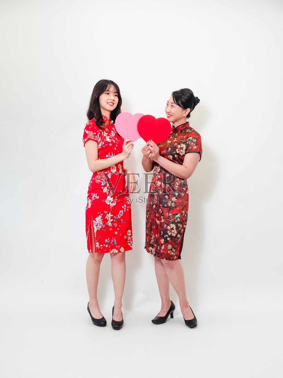 肖像的亚洲妇女都穿着传统旗袍旗袍握着手，心纸形状孤立在白色的背景。照片摄影图片