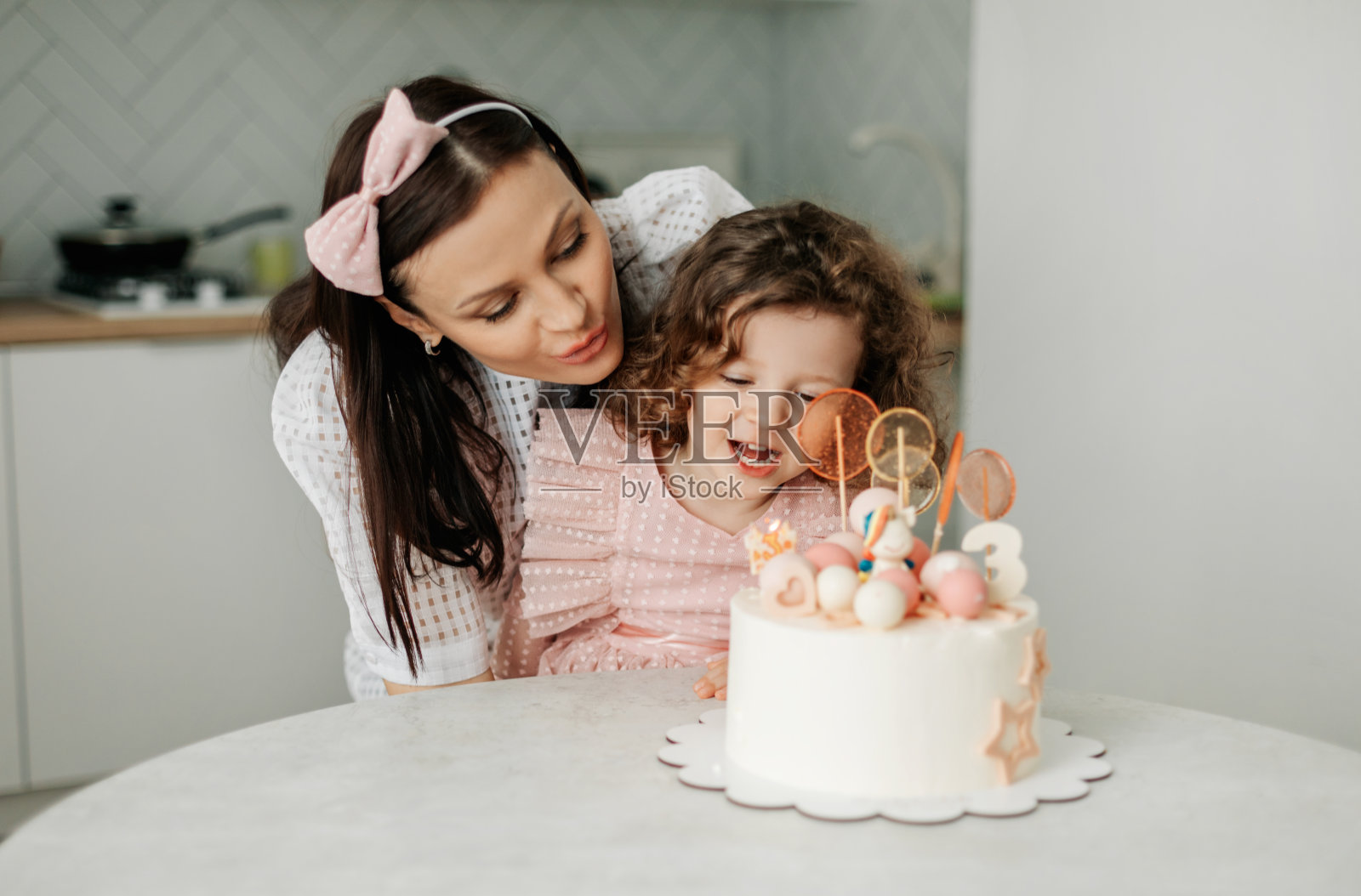 一个迷人的宝宝和她的妈妈吹灭生日蛋糕上的蜡烛照片摄影图片