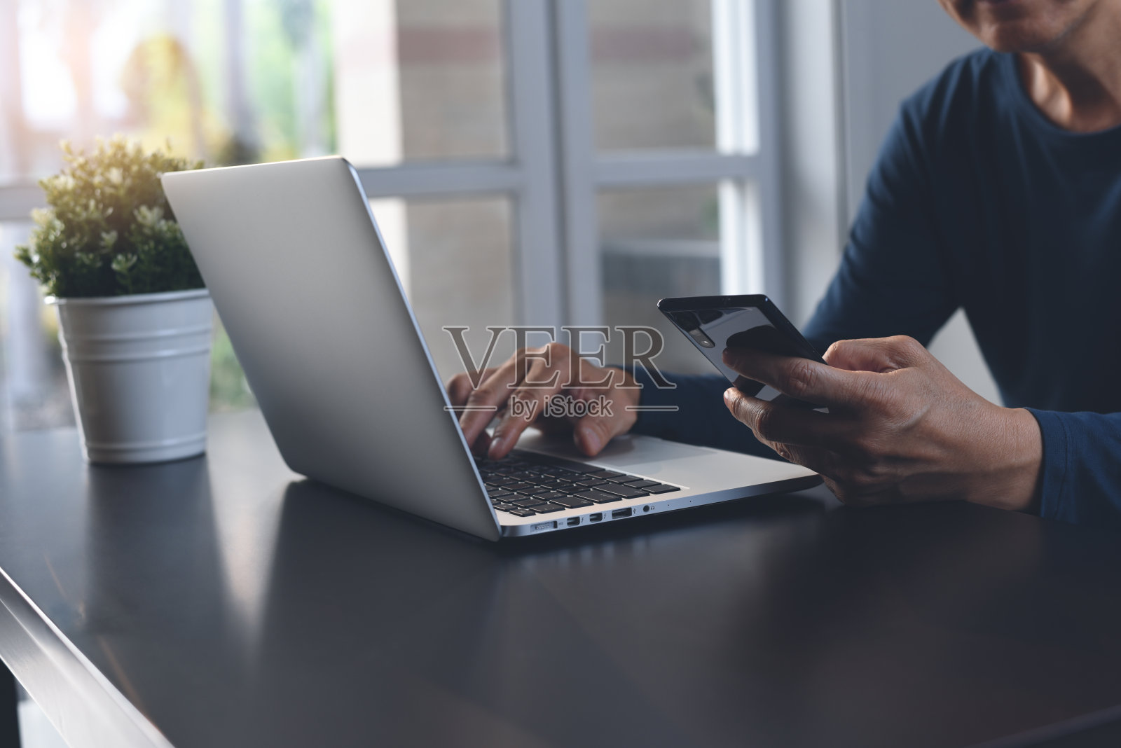 休闲商务人士工作在笔记本电脑和使用移动电话在家庭办公室照片摄影图片