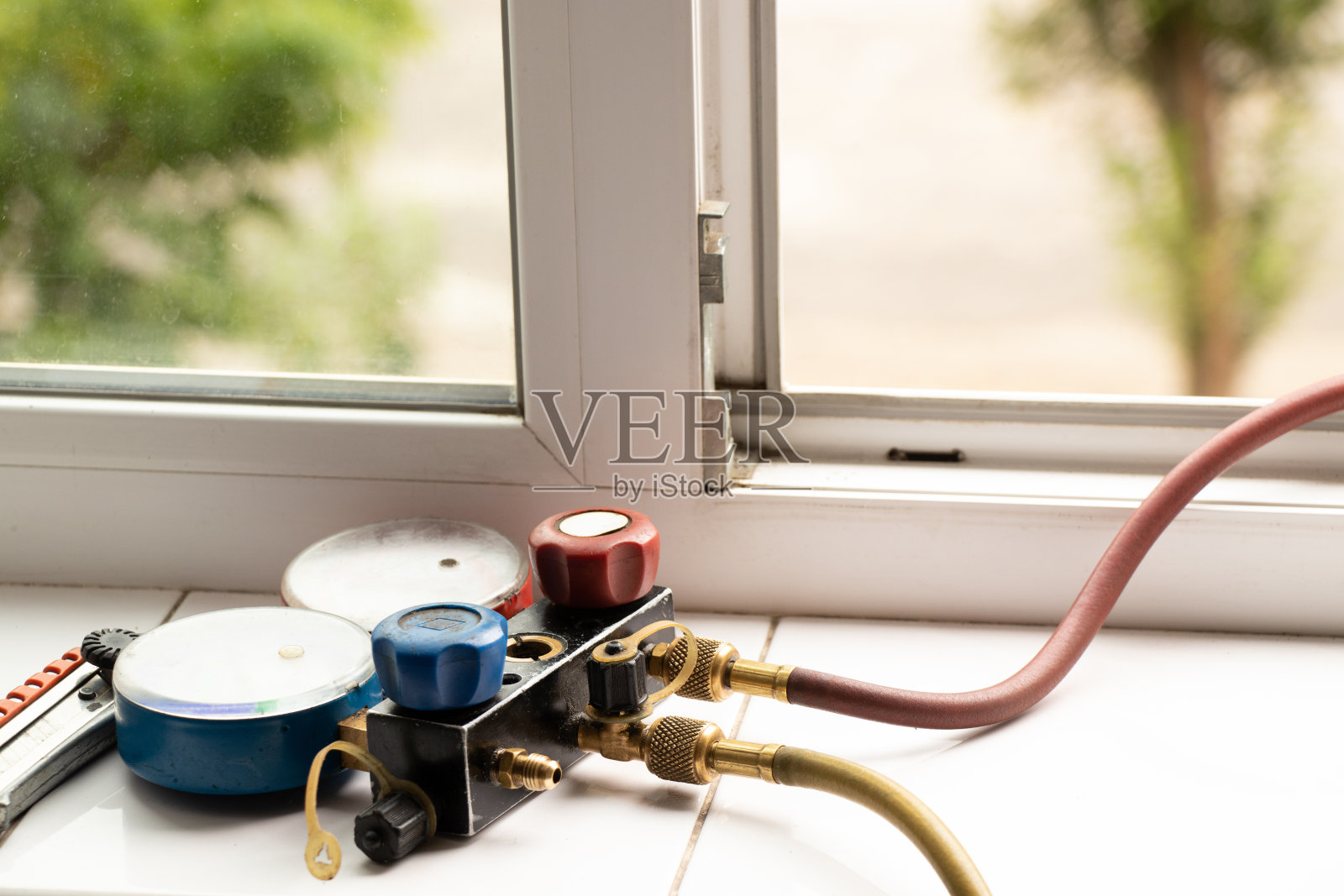 在公寓的窗台上安装了一个双阀测压歧管，用于测量家中空调的压力，维修和诊断空调照片摄影图片