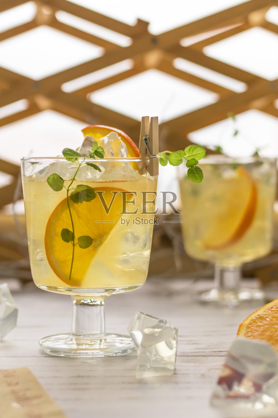 夏天的冰柠檬水，加冰，橘子和薄荷在透明的杯子和鸡尾酒吸管。提神的自制饮料。垂直位置。照片摄影图片