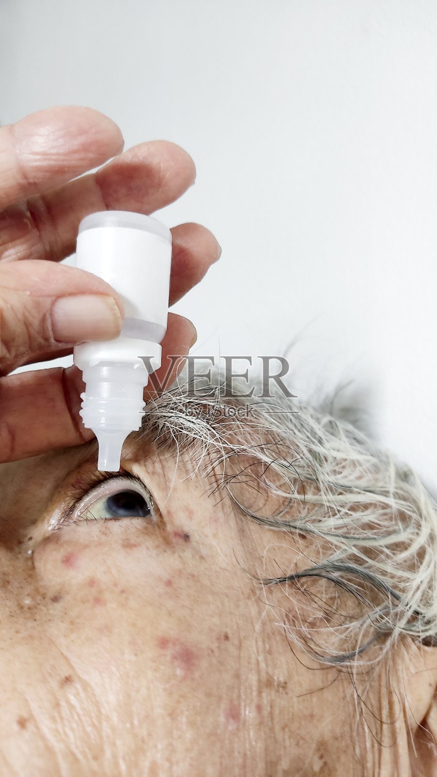 老人在滴眼药水照片摄影图片