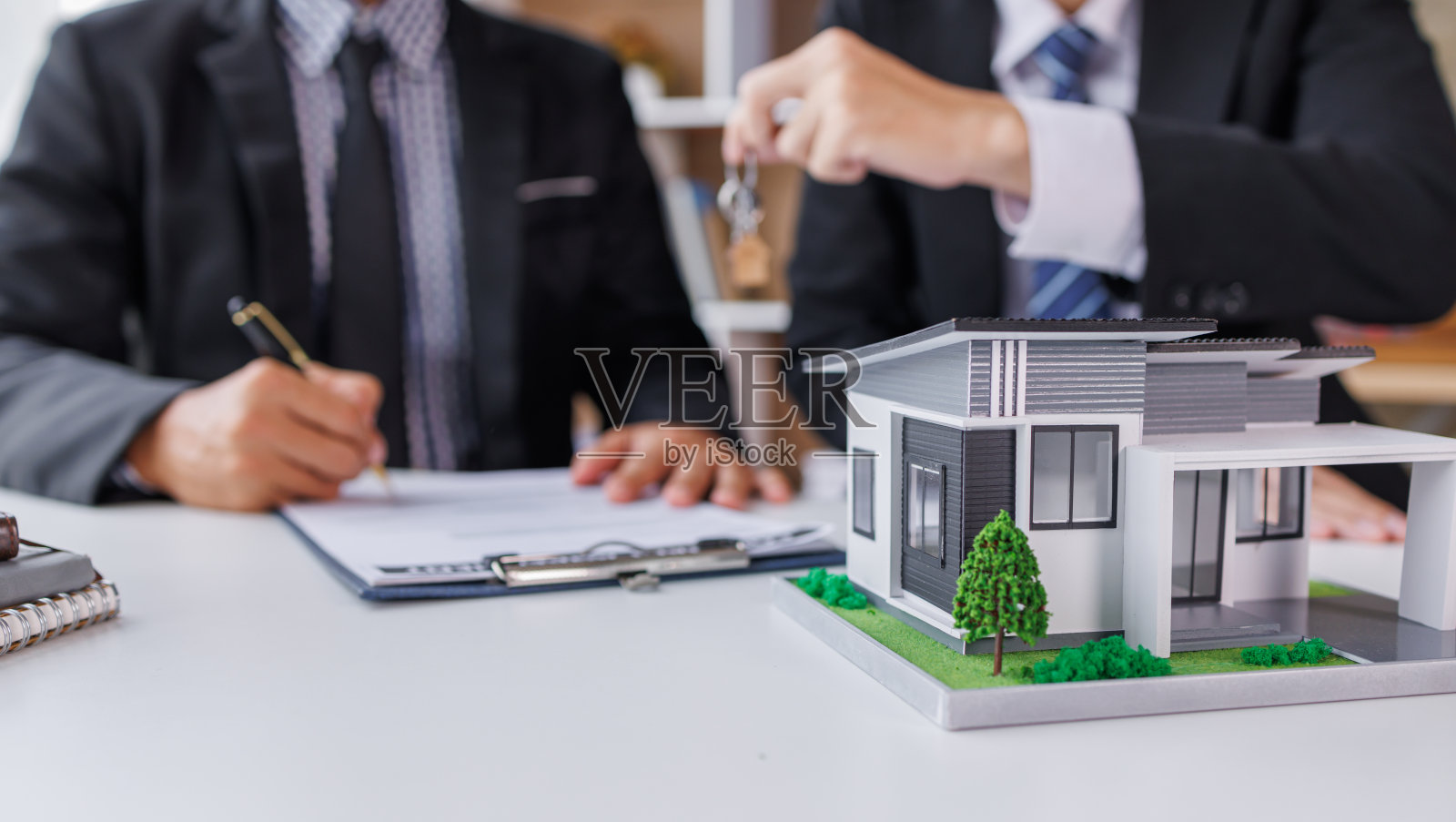房地产经纪人向客户提供和咨询决策签订保单协议，买卖房屋模型，有关按揭贷款报价和房屋保险照片摄影图片
