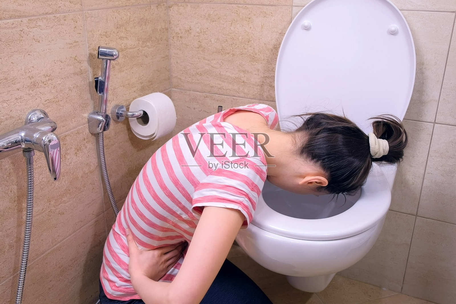 生病的年轻女子在厕所呕吐坐在家里的地板上，有食物中毒的症状。照片摄影图片