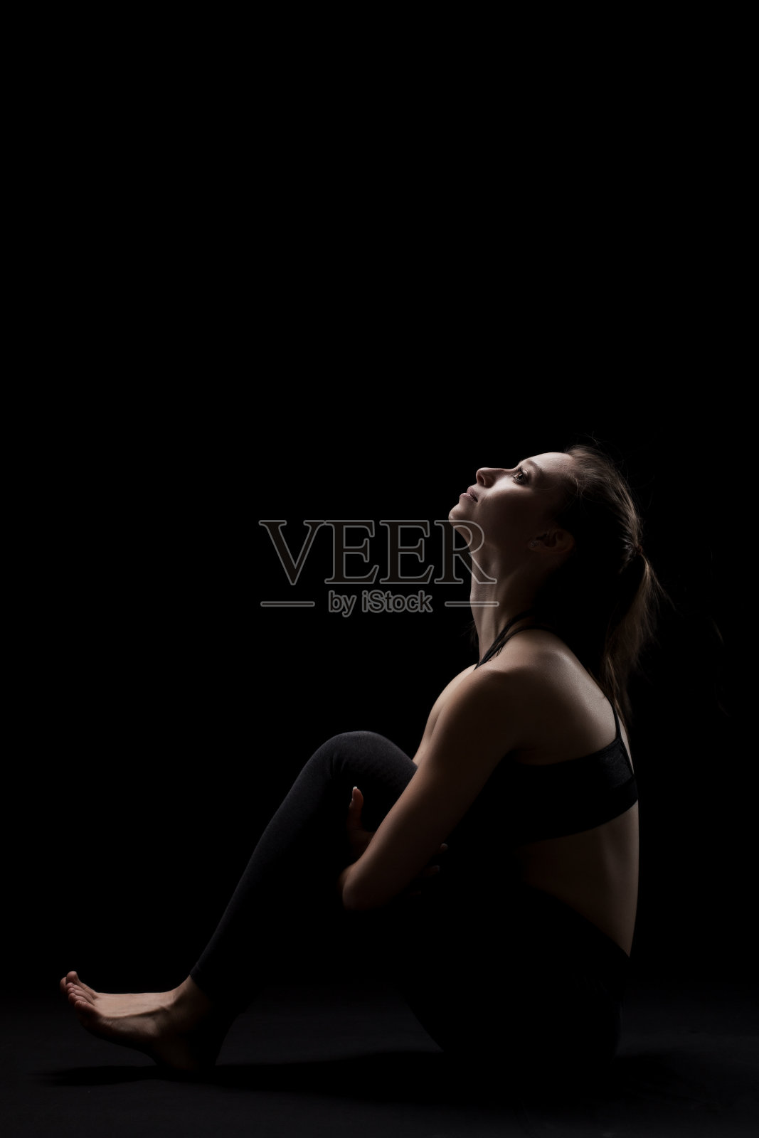 可爱的白人女孩放松瑜伽锻炼后，在黑暗的背景。侧亮轮廓。照片摄影图片