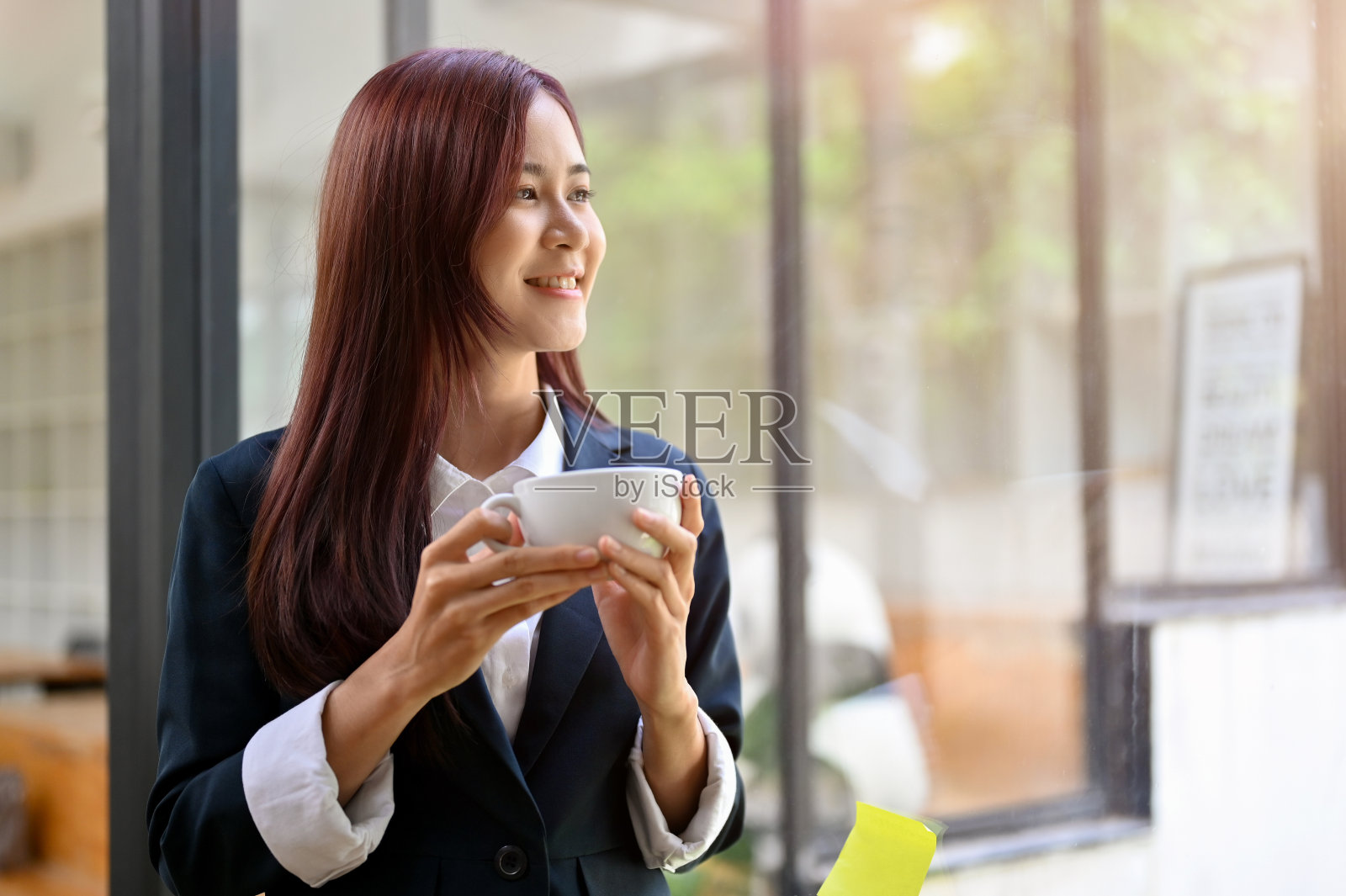 轻松愉快的亚洲女商人拿着咖啡杯，啜饮早晨的咖啡照片摄影图片
