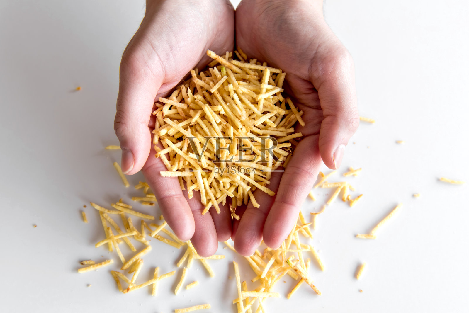 手持稻草土豆的手。照片摄影图片