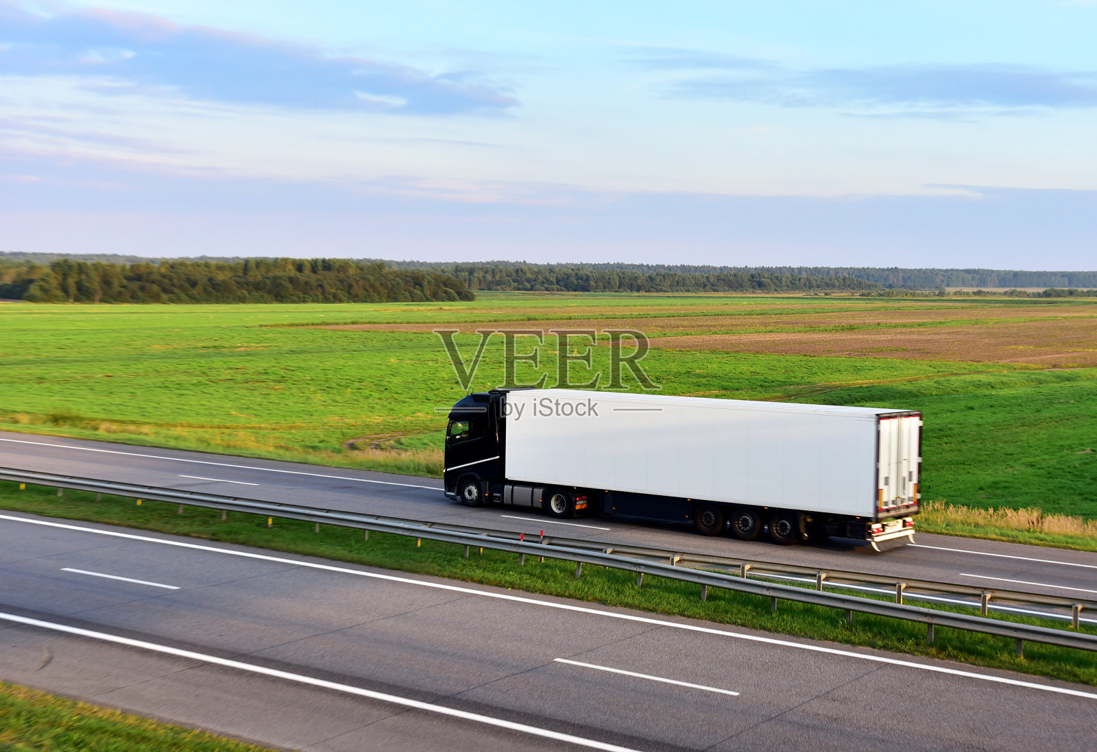 带着半挂车的卡车在日落时分的高速公路上行驶。公路货物运输。服务和运输物流。照片摄影图片