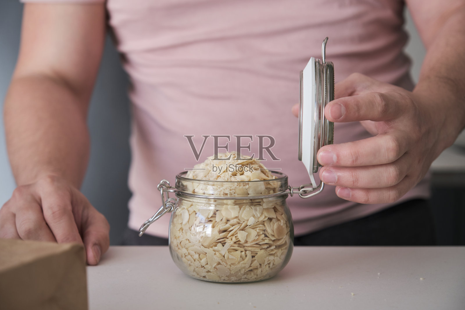 一个不知名的拉丁男人合上一罐焯过水的切片杏仁。照片摄影图片