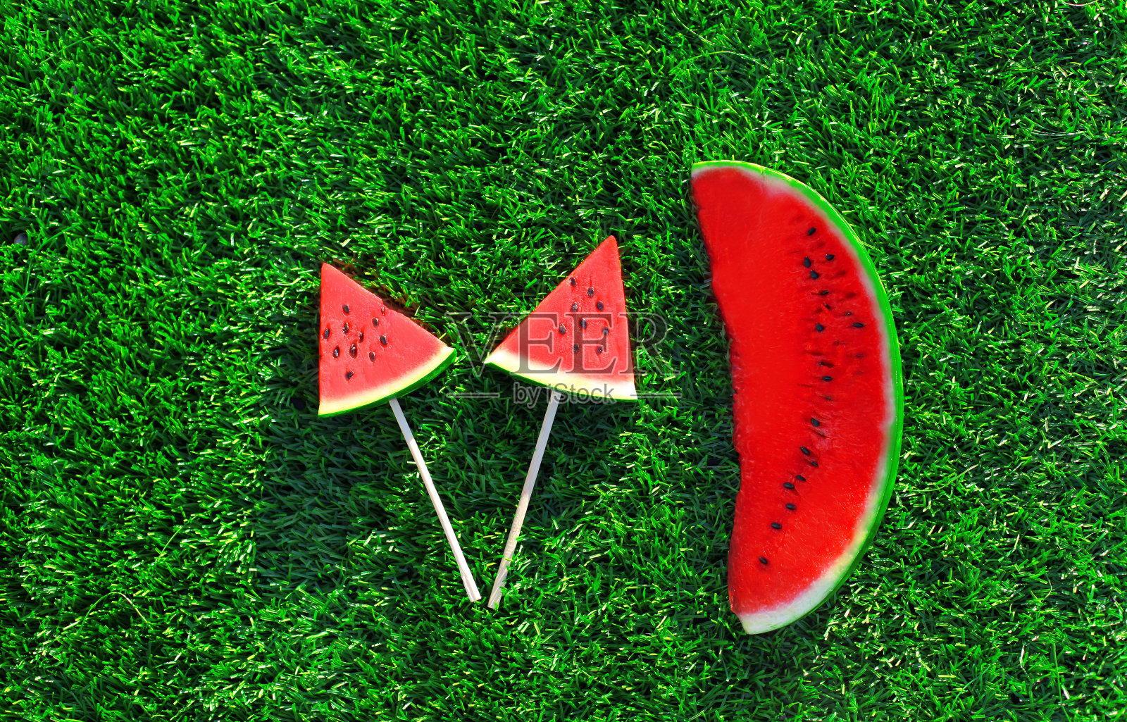 夏天新鲜形象的棒棒糖或冰淇淋形状的西瓜片在草地上的背景照片摄影图片