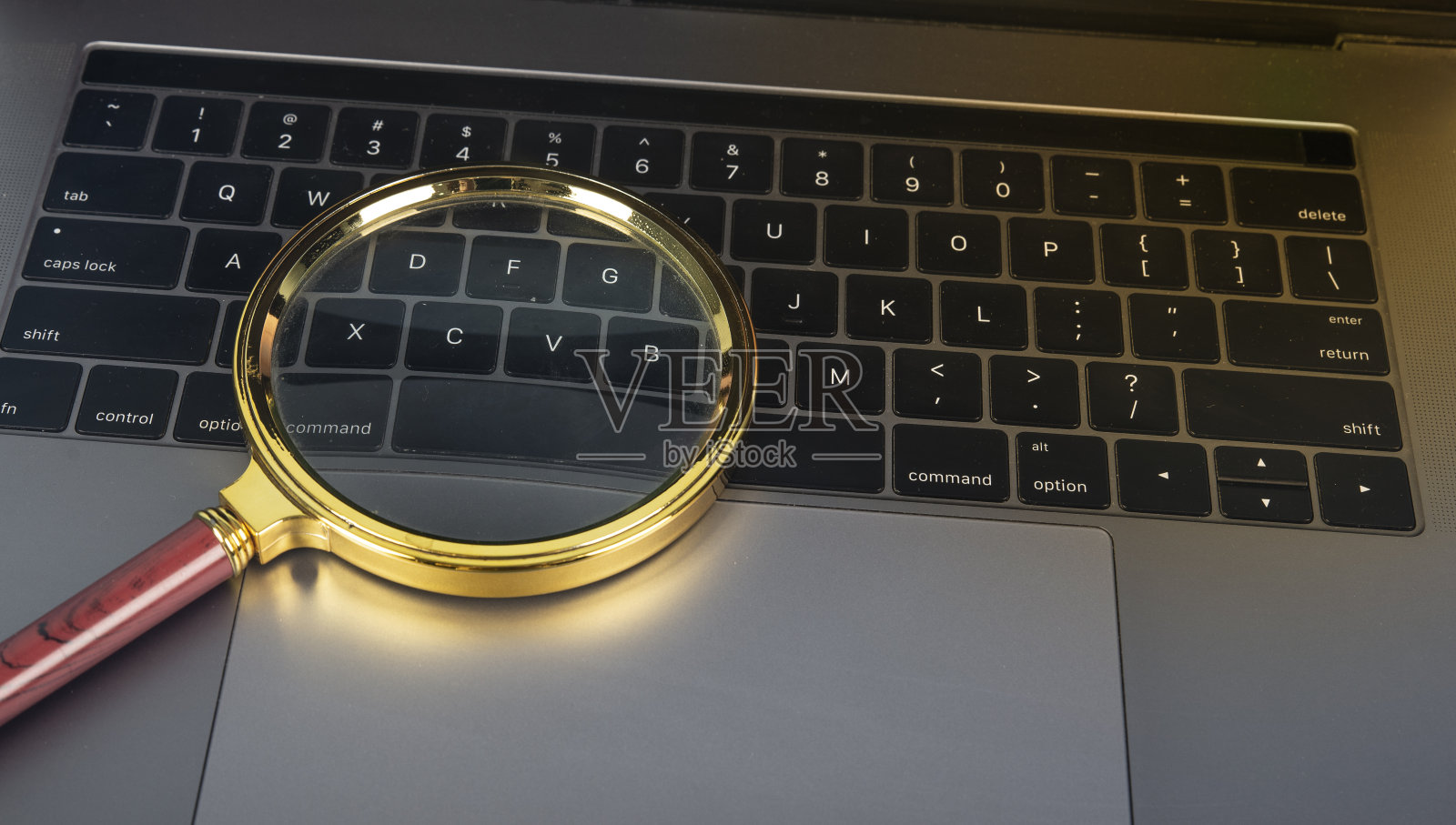 我们在笔记本电脑按键上使用放大镜照片摄影图片