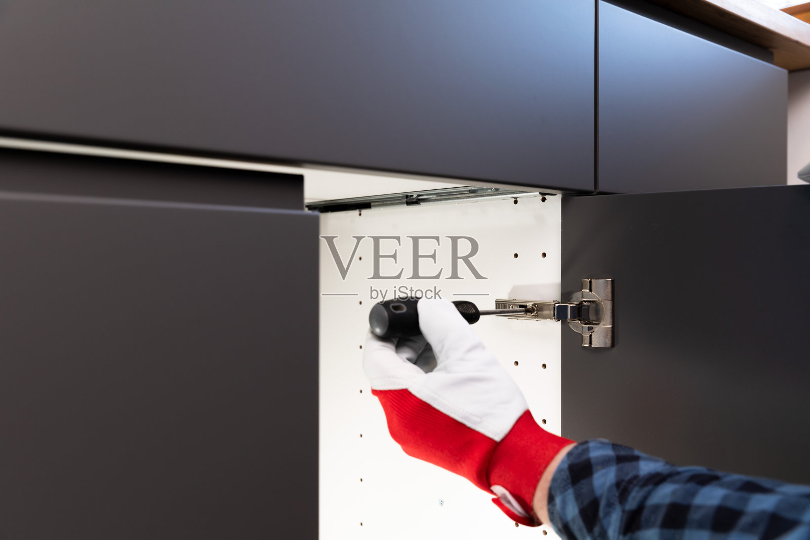 勤杂工在厨房安装门后用螺丝刀测试。平稳而缓慢地闭合。由专业手艺人进行的家装。照片摄影图片